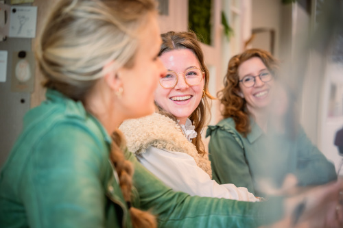 Verloskundigen lachen naar elkaar tijdens een overleg